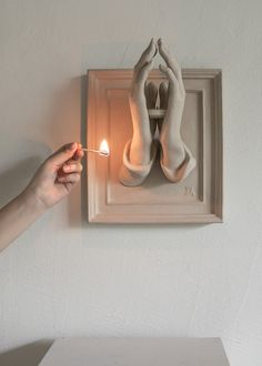 a person lighting a candle in front of a pair of shoes hanging on a wall