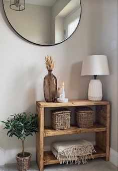 a wooden shelf with baskets under a round mirror