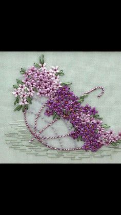 a cross stitch pattern with purple flowers in a white vase