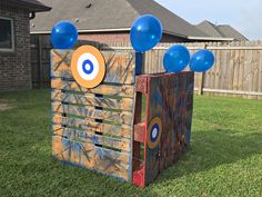 two wooden crates with balloons on them sitting in the grass