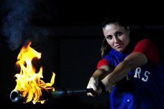 a woman holding a baseball bat over a fire