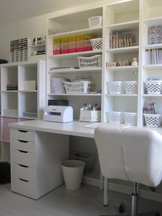 a white desk sitting in front of a book shelf filled with books and other items