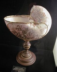 an ornately decorated bowl on display in a glass case with a plaque underneath it