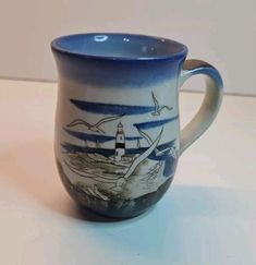 a blue and white coffee cup with a lighthouse on it