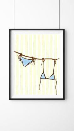 two bikinis hanging on a clothes line in front of a striped wall with a black frame