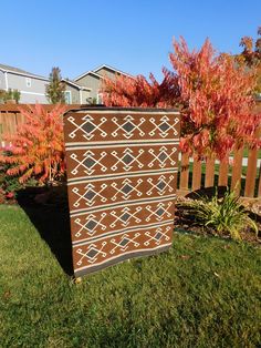 a brown and white dresser sitting on top of a lush green field next to a wooden fence