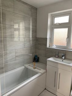 a bathroom with a sink, toilet and bathtub next to a window in it