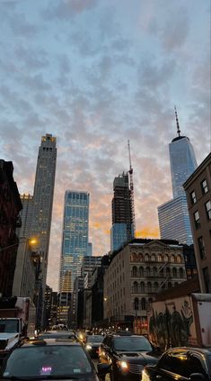 a city street filled with lots of traffic and tall buildings at sunset or dawn in the distance