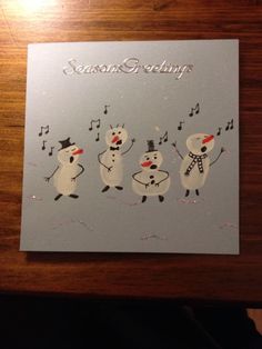 a christmas card with three snowmen and music notes on the front that says seasons greeting