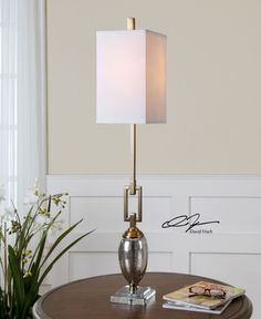 a table with a lamp on top of it next to a potted plant and magazine