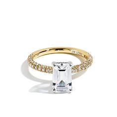 an emerald - cut diamond engagement ring with pave diamonds on the band, set in 18k yellow gold