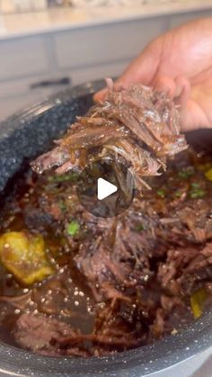 a person is holding a pot roast in a bowl with meat and vegetables on it