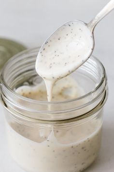 a spoon full of cream sitting on top of a jar filled with something in it