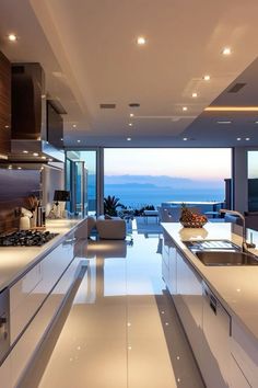 a modern kitchen with white counter tops and stainless steel appliances in front of an ocean view