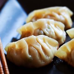 some dumplings are sitting on a plate with chopsticks