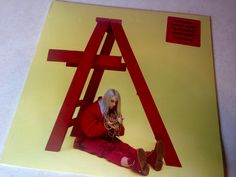 a woman sitting on top of a yellow and red poster with a triangle in the middle