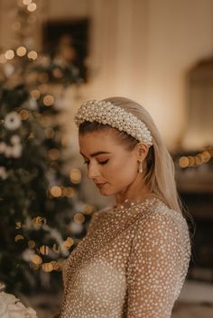 a woman standing in front of a christmas tree wearing a headband with pearls on it