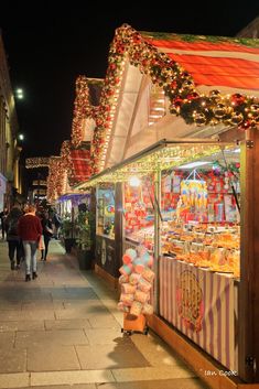 people walking down the street in front of shops decorated with christmas lights