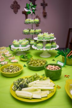 a green table topped with lots of food and cupcakes on top of plates