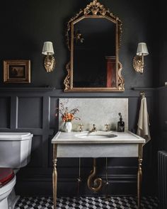 a white sink sitting under a mirror next to a toilet in a room with black walls