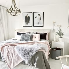 a bedroom with two pictures on the wall and a bed covered in blankets, pillows, and throws