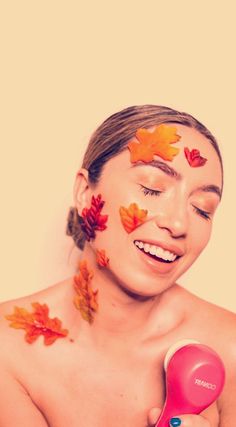 a woman with leaves on her face holding a hair dryer