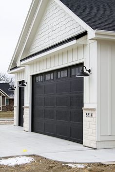 a black and white house with two garages