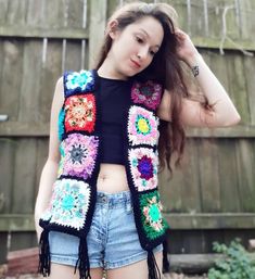 a young woman wearing shorts and a crocheted vest with flowers on the sides