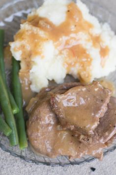 a glass plate with mashed potatoes, green beans and gravy