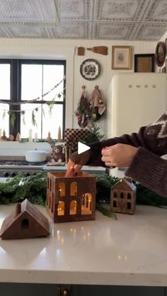 a woman standing in front of a kitchen counter with christmas decorations on top of it