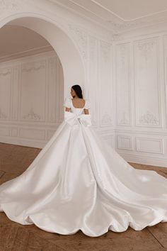 a woman in a white wedding dress is standing on the floor with her back to the camera