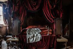 an old fashioned bedroom with red drapes and curtains