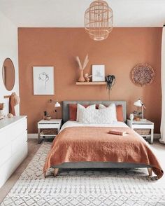 a bedroom with an orange and white color scheme on the walls, bedding and pillows