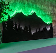 an image of a green light in the night sky over mountains and trees on a table