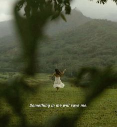 a woman in a white dress standing on top of a lush green field under a cloudy sky