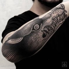 a man with a black and white tattoo on his arm holding up a large fish