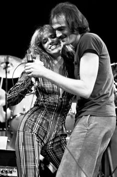 a man and woman on stage with microphones in their hands, one holding the other's head