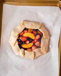 a pastry with fruit in it sitting on top of wax paper and gold serving tray