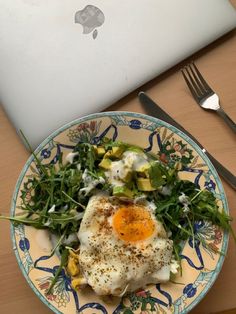 an open laptop computer sitting on top of a table next to a plate with food