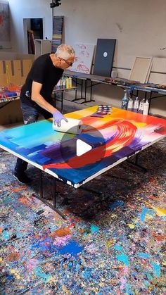 a man is painting on a table in an art studio