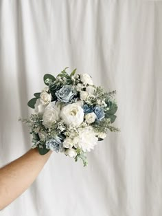 a person holding a bouquet of white and blue flowers