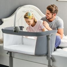 a man and woman sitting on top of a bed next to a baby crib