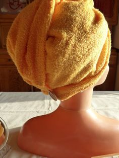 a bathrobe on top of a mannequin's head next to a bowl of oranges