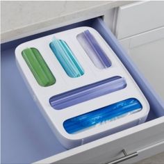 an open drawer with three different colored toothbrushes in it