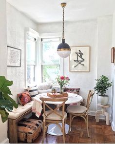 a dining room table with chairs and a bench in front of a window next to a potted plant