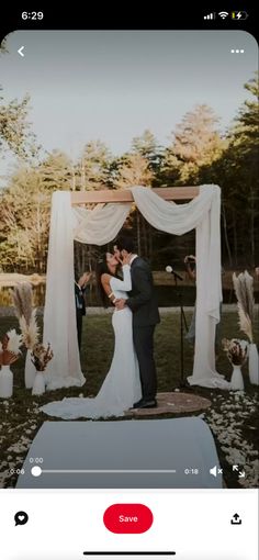 a couple kissing in front of an outdoor wedding ceremony with white drapes and flowers