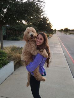 a woman holding a dog on the sidewalk