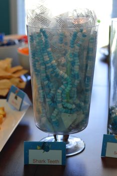 there are many small beads in a glass vase on the table next to crackers