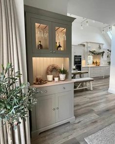 a kitchen with grey cupboards and white walls, wooden floors and an area rug on the floor that has a potted plant in it