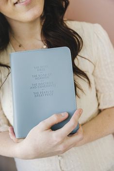 a woman holding a blue book with writing on the front and back cover in her hands